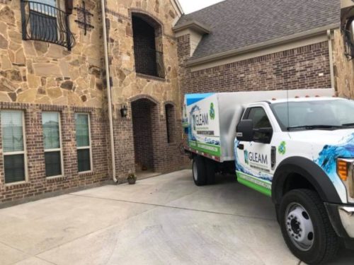 A GLEAM truck operator prepares to pressure wash a driveway